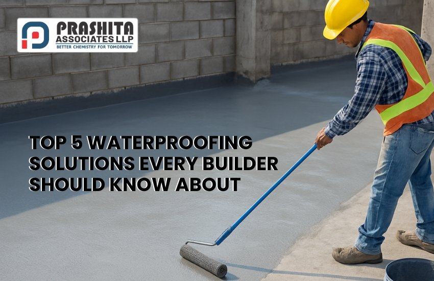 A construction worker in a yellow hard hat and reflective vest is applying a grey waterproofing coating on a concrete floor using a long-handled roller. The Prashita Associates LLP logo appears in the top-left corner, along with the text: “Top 5 Waterproofing Solutions Every Builder Should Know About.